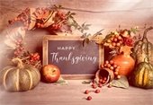 pumpkins, fall leaves, and wreaths surround a chalkboard that reads happy thanksgiving