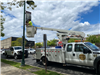 DPW employee in truck hanging a banner from a lamppost