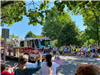image of firetruck driving down a street lined with people waving flags for memorial day