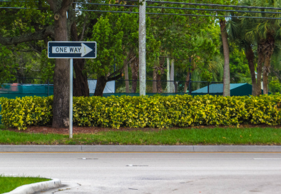 photo of a street with a one way road sign in the back