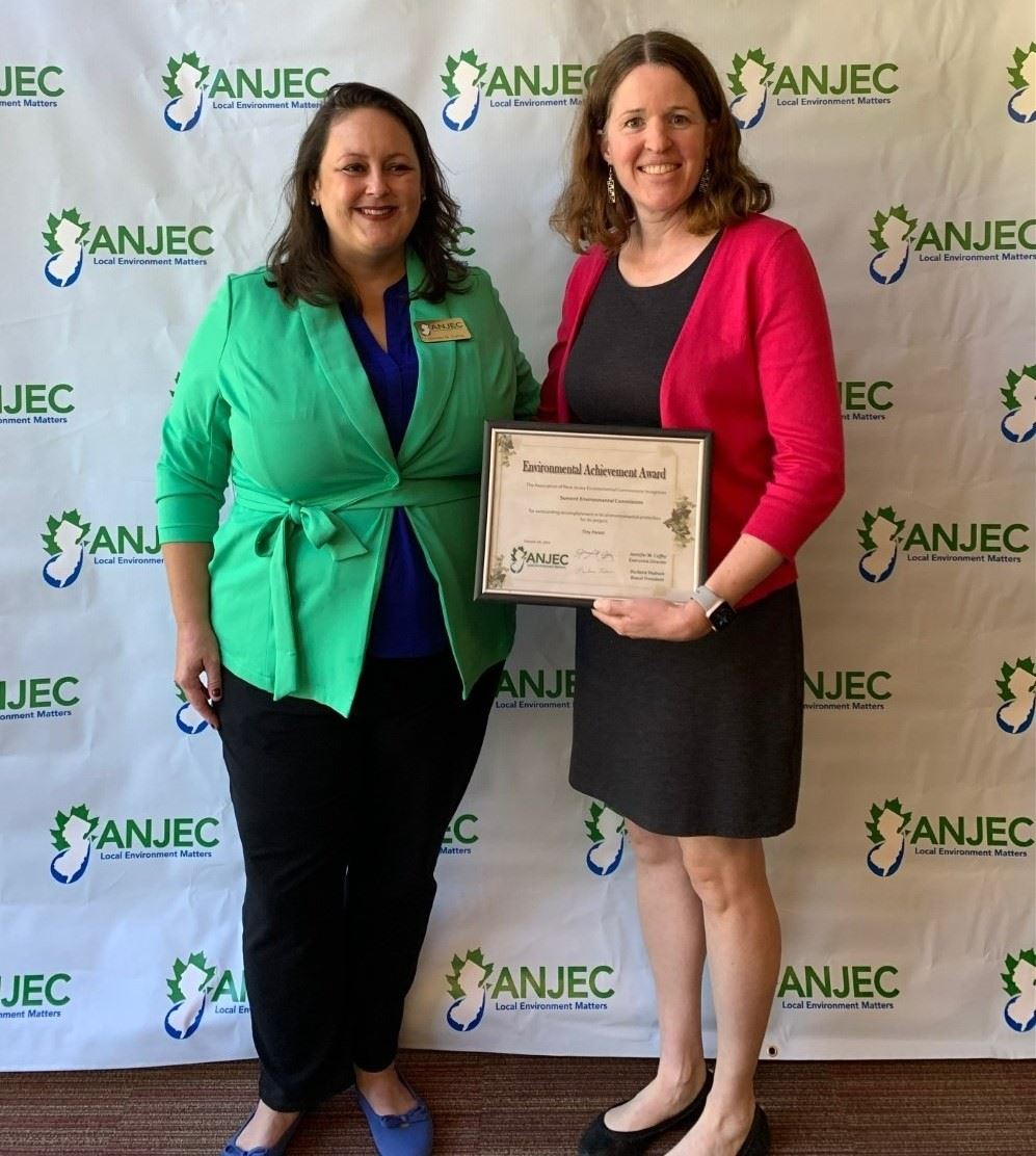 image of two women posing for a photo, one is holding up an award