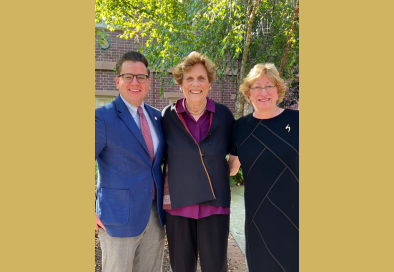 image of three people posing for a photo with trees and a brick building in the background