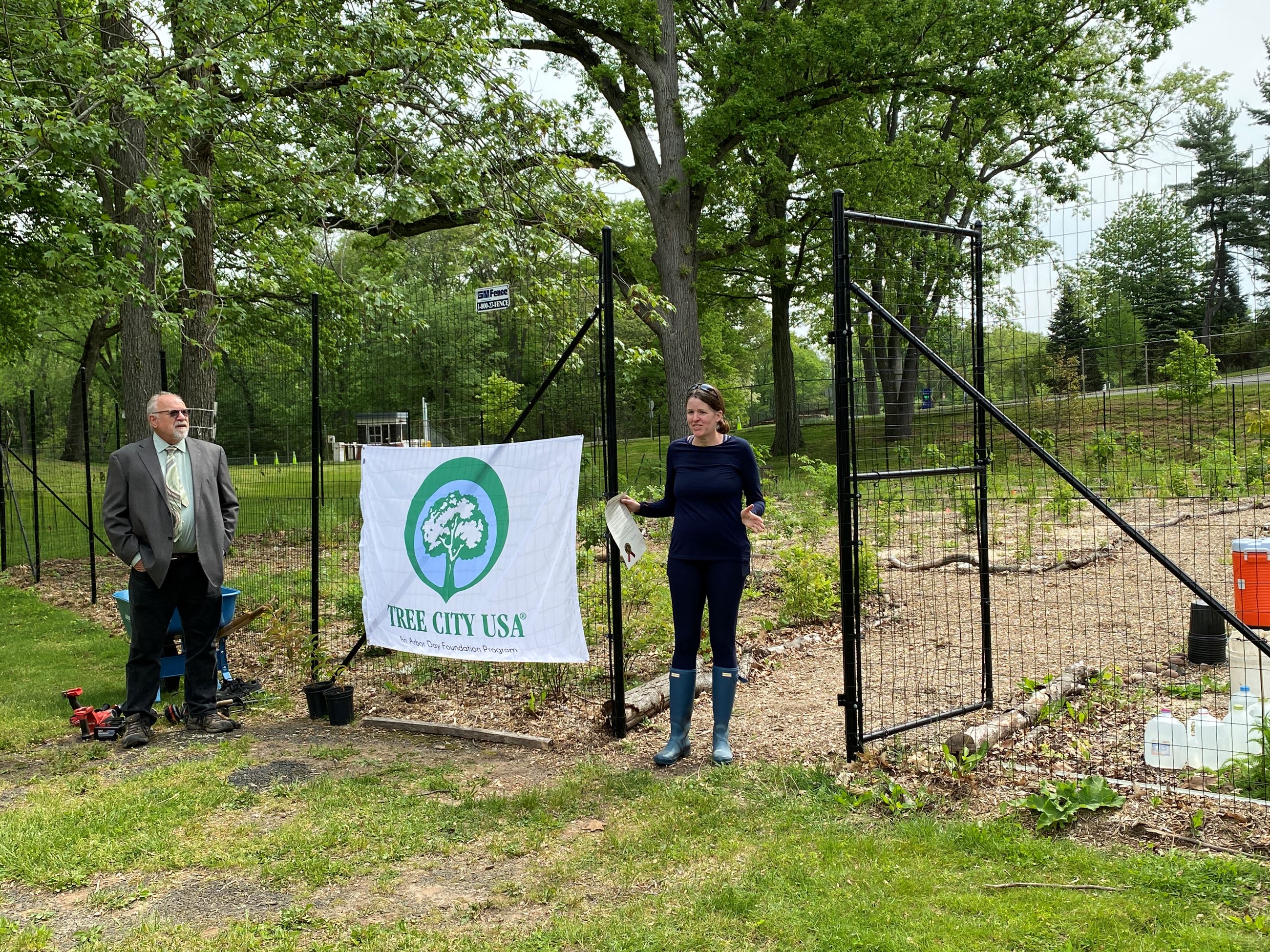 two people in front of fenced off grassy park area