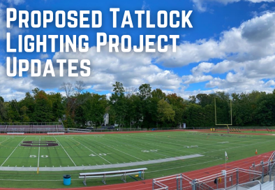 green field with red track and blue cloudy sky