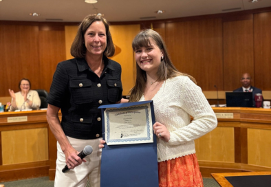 mayor and student posing for photo with certificate in council chamber