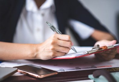 Stock photo of someone signing a form on a clipboard