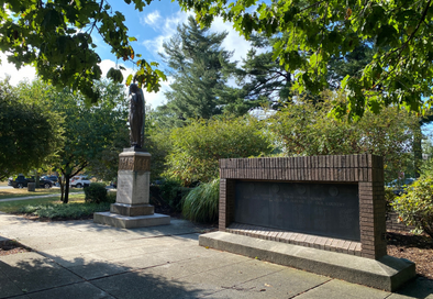 photo of monuments on village green with trees and blue sky in the background
