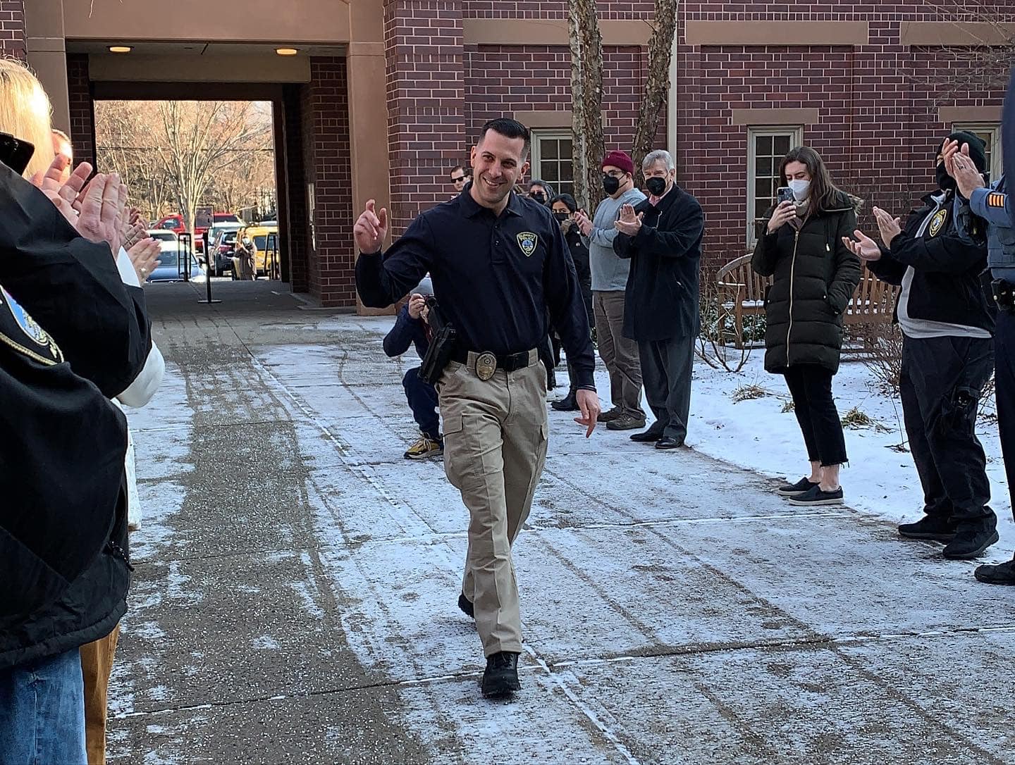 Image of Officer Pyzik walking through the courtyard of City Hall with people lined up along the sides