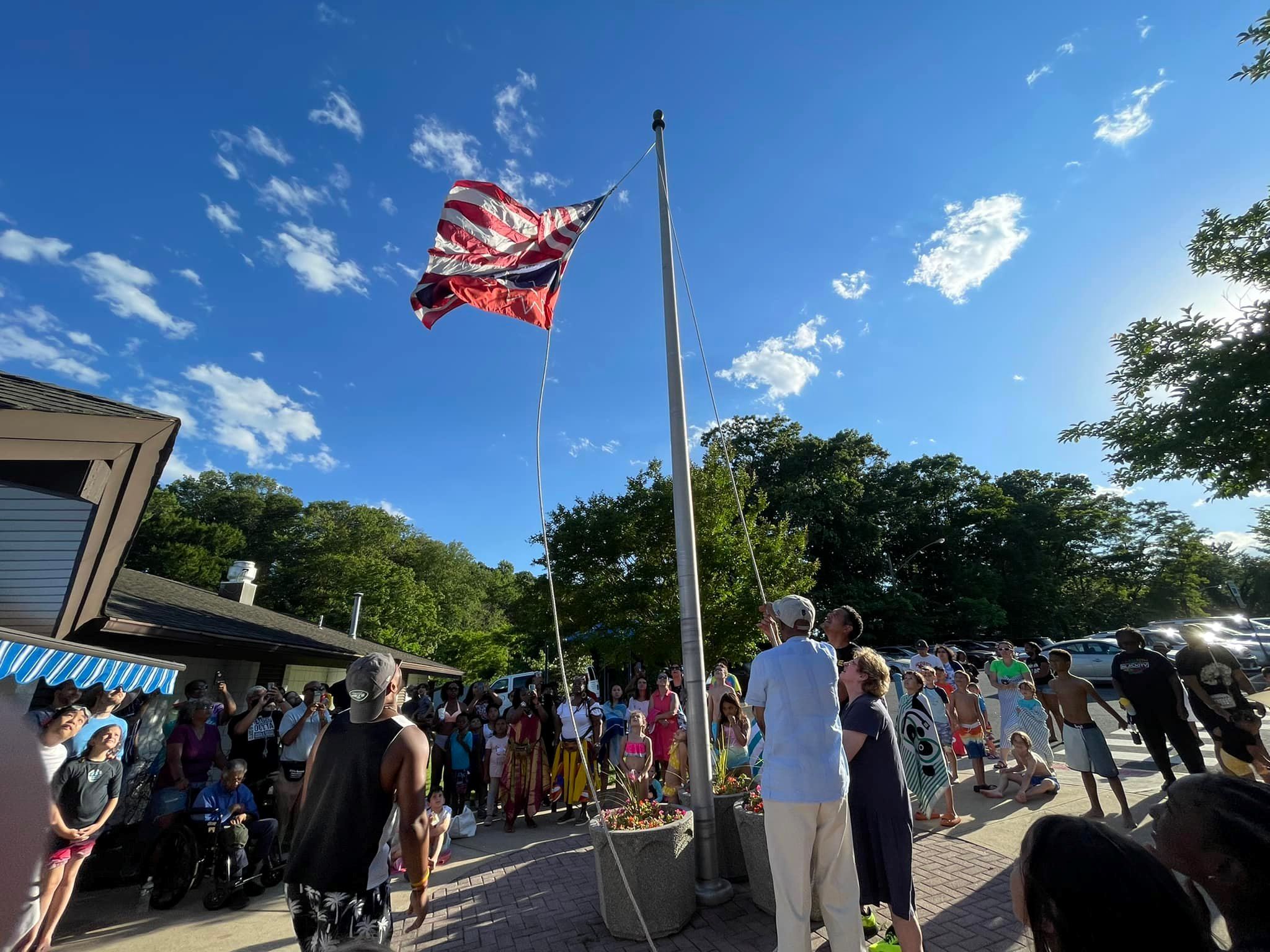 image of group of people gathered around a flagpole for Juneteenth event