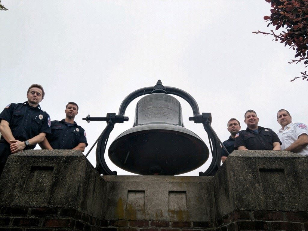 group photo of firefighters gathered around memorial bell