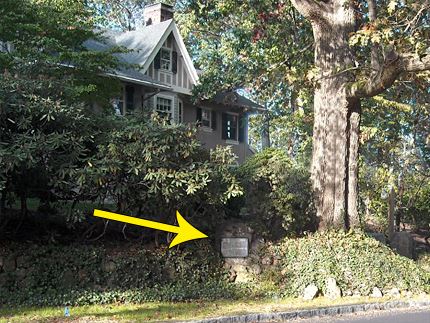 Plaque near house with yellow arrow pointing to the plaque